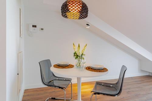 a white table with chairs and a vase of flowers at Edificio 13 by Plaza Mayor Apartamentos in Valladolid