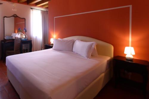 a bedroom with a white bed with an orange wall at Classique in Lazise