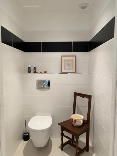 een badkamer met een wit toilet en een stoel bij Les Jardins de Quatrina 2 chambres vue mer in Propriano