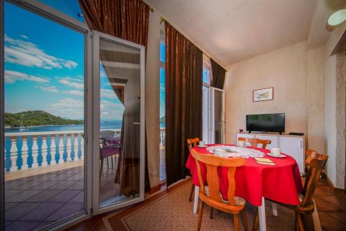 a dining room with a table and a balcony at Apartments Filipović in Sobra