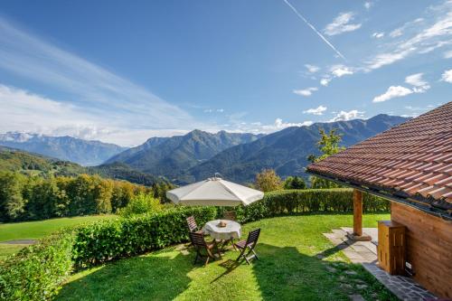 un patio con ombrellone, tavolo e sedie di Baita Nido tra i Monti a Daone