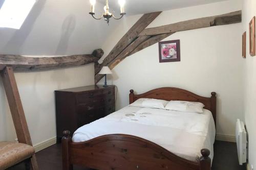 um quarto com uma cama de madeira e lençóis brancos em Our home in the medieval village of Sancerre em Sancerre