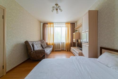 Habitación de hotel con cama y silla en Apartments on Ploscha Yakuba Kolasa en Minsk