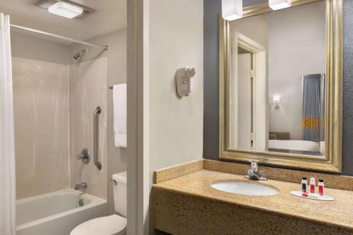 ein Badezimmer mit einem Waschbecken, einem WC und einem Spiegel in der Unterkunft Baymont by Wyndham Wilmington in Wilmington