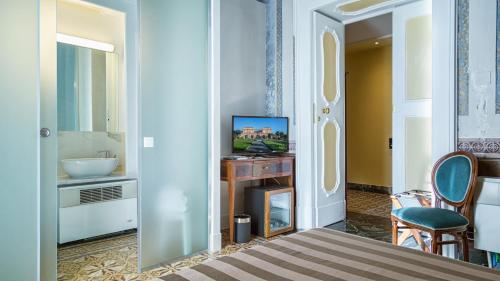 a room with a television and a table with a chair at Villa Signorini Hotel in Ercolano