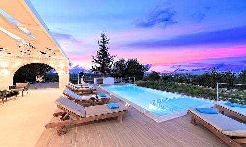 a swimming pool with a sunset in the background at Orientem Villa Heated Pool in Georgioupoli