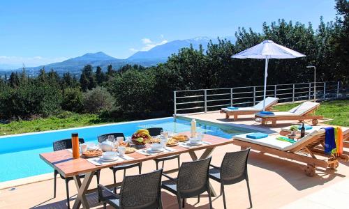 a patio with a table and chairs next to a pool at Orientem Villa Heated Pool in Georgioupoli