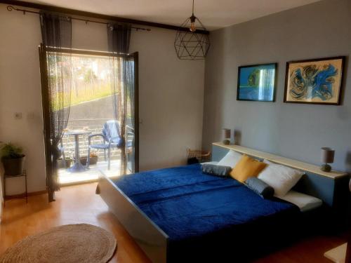 a bedroom with a blue bed and a window at Apartments Asija in Brela
