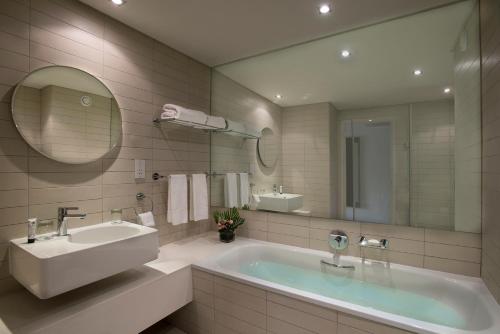 a bathroom with a tub and a sink and a mirror at Labadi Beach Hotel in Accra