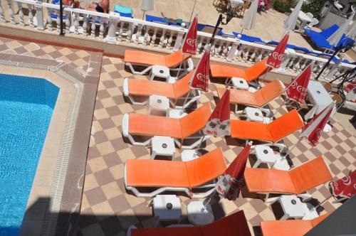 einen Blick über den Pool mit orangefarbenen Liegestühlen in der Unterkunft BASILS APART HOTEL in Marmaris
