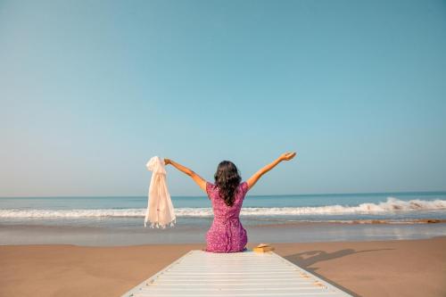 a woman in a pink dress sitting on the beach at Malabar Ocean Front Resort And Spa, Bekal in Nīleshwar