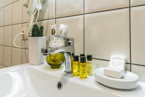 Hotel Flower في تبليسي: مغسلة الحمام يوجد عليها صنبور وزجاجات