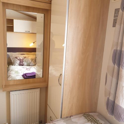 a small bedroom with a mirror and a bed at Deer lodge in Auchterarder
