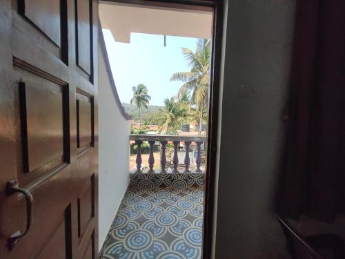 an open door to a balcony with palm trees in the background at Baga View Inn in Baga