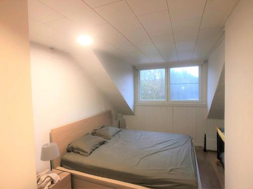 Un dormitorio con una cama en una habitación con ventana. en De Tureluur, en Cadzand