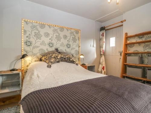 a bedroom with a bed with a headboard and a shelf at Tiny Willow in Blandford Forum