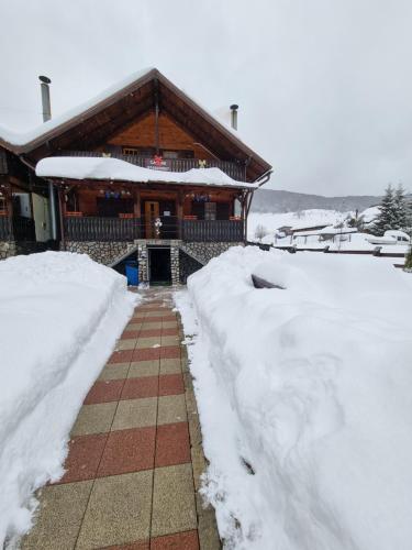ein schneebedecktes Haus neben einem Bürgersteig in der Unterkunft Freemont in Braşov
