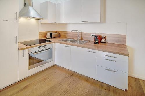 une cuisine avec des armoires blanches et un plancher en bois dans l'établissement IMMOGROOM - 5min from the Festival Palace - AC - Wifi - Center, à Cannes