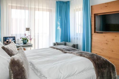 a bedroom with a large bed and a television at Das Aunhamer Suite & Spa Hotel in Bad Griesbach