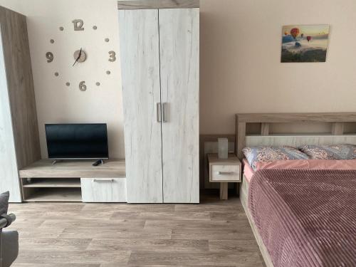 - une chambre avec un lit et une armoire avec une télévision dans l'établissement Уютные апартаменты на Тверском проспекте, à Tver