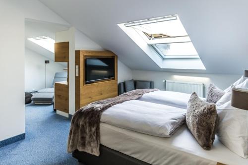 een slaapkamer met een groot bed en een dakraam bij Das Aunhamer Suite & Spa Hotel in Bad Griesbach
