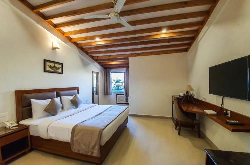 a bedroom with a bed and a desk and a television at LP Residency in Dehradun
