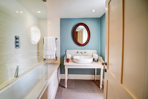 a bathroom with a sink and a tub and a mirror at High Force Hotel in Newbiggin