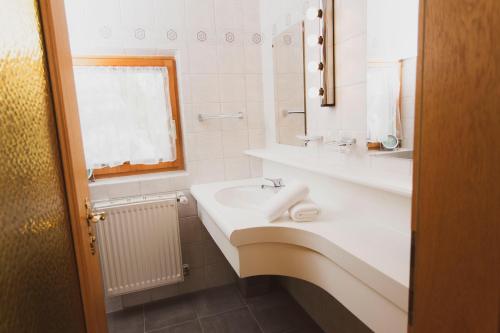 a white bathroom with a sink and a mirror at Lesachtalerhof in Liesing