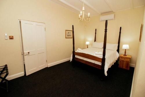 a bedroom with a four poster bed and a chandelier at De Kothuize 7 in Graaff-Reinet
