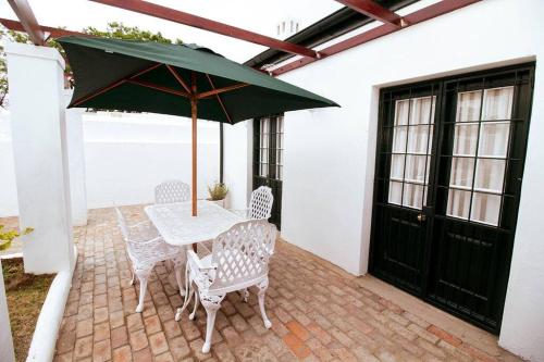 a table and chairs with an umbrella on a patio at De Kothuize 7 in Graaff-Reinet