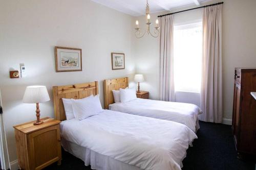 a bedroom with two beds and a window at De Kothuize 7 in Graaff-Reinet