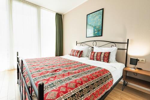 a bedroom with a large bed with a red blanket at Hotel Flower in Tbilisi City
