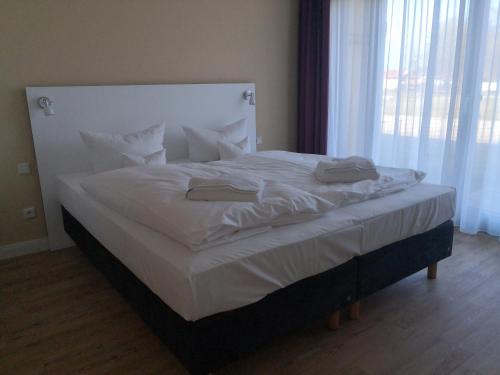 a bed with white sheets and pillows in a bedroom at Die Remise Oleander RE-06 in Stolpe