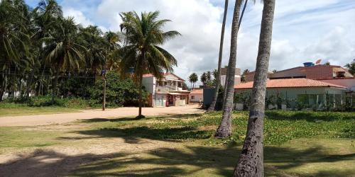 a group of palm trees in front of a house at Pousada Beach Claudia in Maragogi