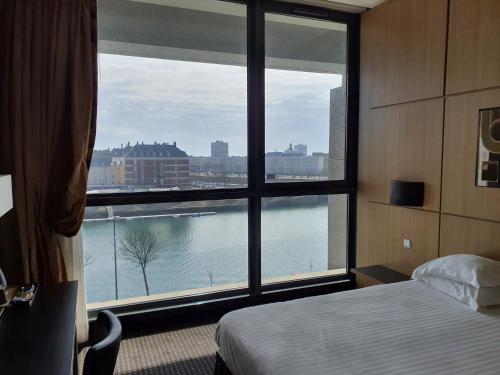 ル・アーヴルにあるHotel Spa Le Pasinoのベッドルーム1室(水辺の景色を望む大きな窓付)