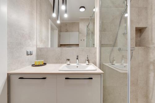 a bathroom with a white sink and a shower at 4 Seasons Jelitkowo + Beach in Gdańsk