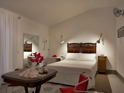 a bedroom with a large white bed and a table at La Moresca Maison De Charme in Marina di Ragusa