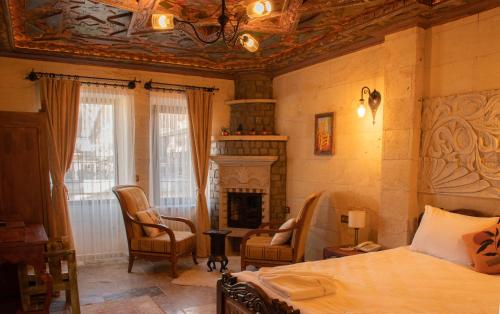 a bedroom with a bed and chairs and a fireplace at Olivia Cave Hotel in Göreme