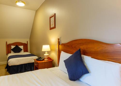 a hotel room with two beds and a lamp at Tudor House Guest House in Dungarvan