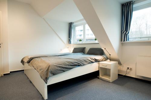 1 dormitorio con 1 cama blanca y 2 ventanas en fewo1846 - Baltic Lodge - komfortable Maisonettewohnung mit 3 Schlafzimmern, Balkon und Blick auf die Marina Sonwik, en Flensburg
