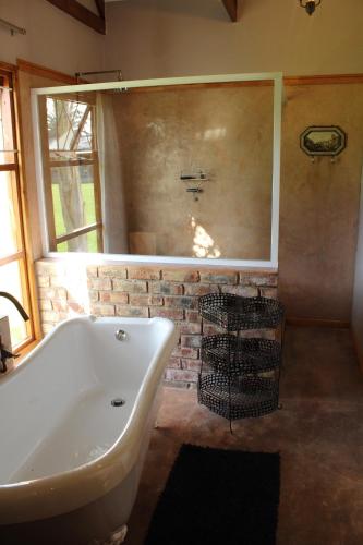a bathroom with a white tub and a brick wall at Lentelus Guesthouse in George