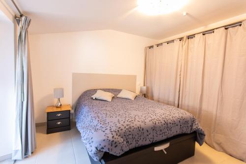 a bedroom with a bed and curtains in it at Le bélier 2nd étage avec balcon au centre ville d'Embrun climatisé in Embrun