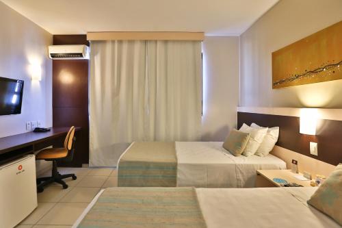 a hotel room with two beds and a desk at Comfort Hotel Goiânia in Goiânia