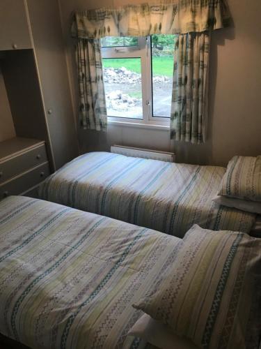 two beds in a small room with a window at Stonygarth Cabin in Crosby Garrett