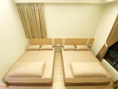 two beds in a small room with a window at Amadel Residence 爱媄德民宿 16 in Melaka