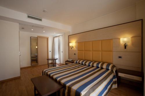 a hotel room with a bed with a striped blanket at Virgilio Grand Hotel in Sperlonga