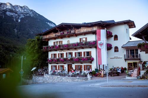 a large building with people sitting outside of it at Hotel Mariasteinerhof in Mariastein