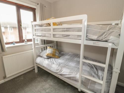 a white bunk bed in a room with a window at 40 Lloyd Street West in Llandudno