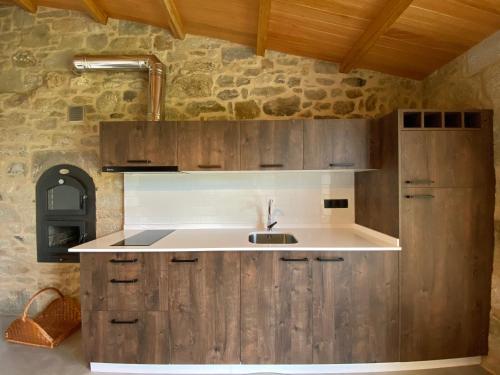 a kitchen with a sink and a stone wall at Lugar das Marías in Jove