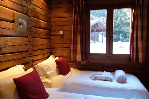 una camera con 2 letti in una baita di tronchi di Madame Vacances Chalet Elliot Est a La Perrière